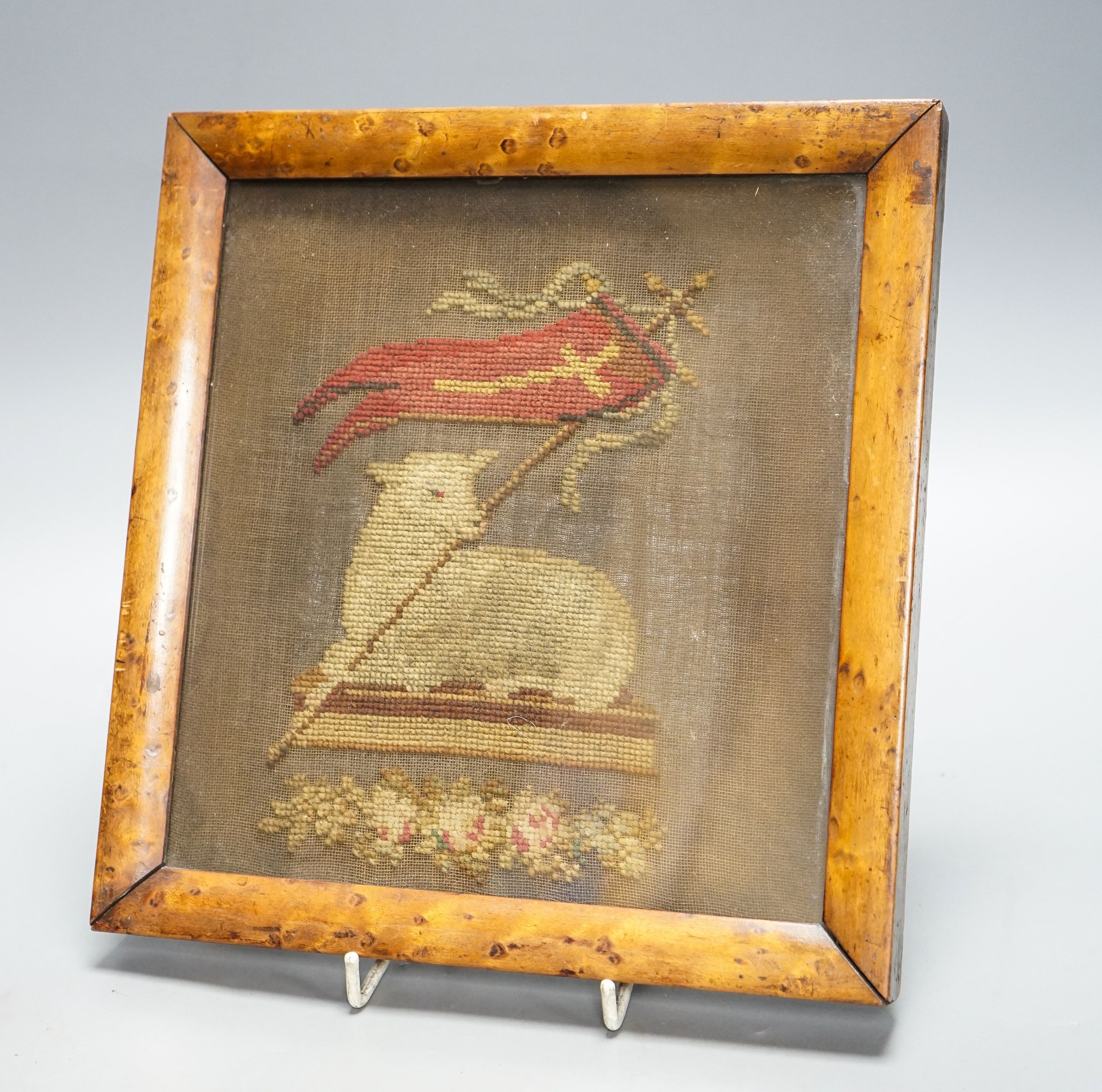 An early 19th century needlework of the Agnus Dei with the vexillum, incorporating a lamb and flag, in bird's eye maple frame 25x23cm incl frame